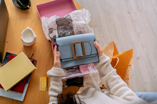A woman unboxing a new purse from her luxury packaging.