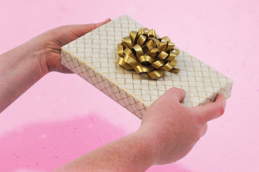 A beautifully wrapped gift with a gold colour scheme that emphasises the connection between giver and the psychology behind gift wrapping