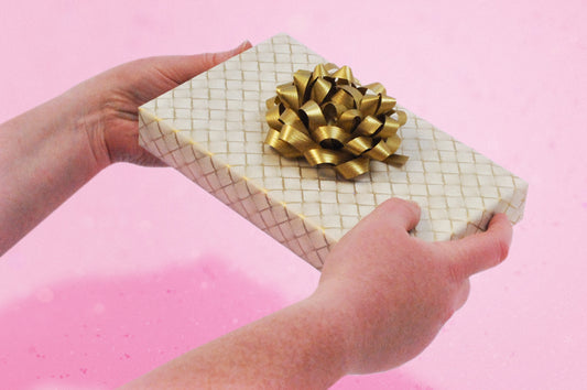 A beautifully wrapped gift with a gold colour scheme that emphasises the connection between giver and the psychology behind gift wrapping   